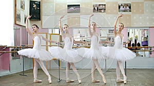 in ballet hall, girls in white ballet skirts are engaged at ballet, rehearse tendue forward battement, Young ballerinas