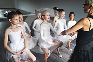 Ballet teacher and students ballerinas exercising in dance class in school