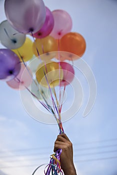 Balloon Hand in Happy birthday party sky background with string and ribbon helium Ballon floating in celebrate wedding day.Concept