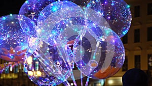 Balloons with colorful LED lights are sold on the night street of the old city center.