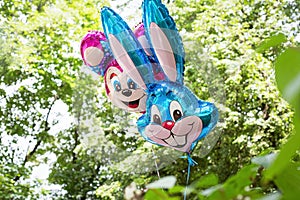 Balloons filled with helium in form of rabbit and mouse in children\'s park against backdrop of green trees. Concept: gifts,