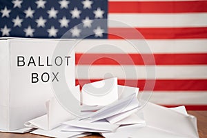 Ballot Box with votes on table before counting with US flag as background concept of Ballot or vote Counting after US election photo