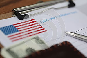 Ballpoint pen and dollar bills lying on documents for applying for visa closeup