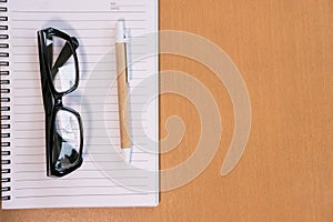 ballpoint pen, empty notebook, eyeglasses on office desk. business, education concept. Top view with copy space. selective focus.