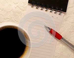 A ballpoint pen lies on a blank lined page from a spiral notebook