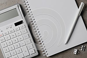 Ballpoint pen, notebook and calculator on gray table, flat lay