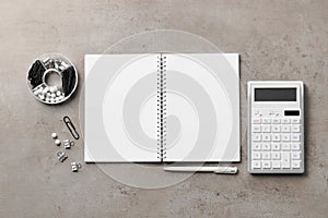 Ballpoint pen, notebook and calculator on gray table