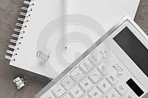 Ballpoint pen, notebook and calculator on gray table, flat lay