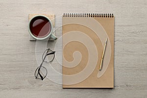 Ballpoint pen, notebook and cup of tea on wooden table, flat lay