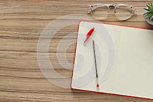 Ballpoint pen, notebook and glasses on wooden table, flat lay. Space for text