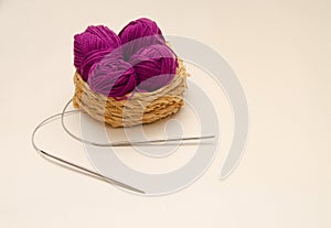 Balls of colored knitting threads and knitting needles on a white background