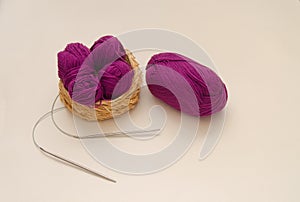 Balls of colored knitting threads and knitting needles on a white background