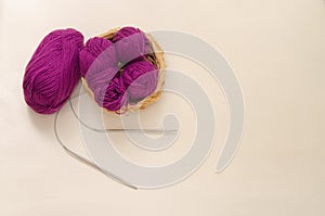 Balls of colored knitting threads and knitting needles on a white background