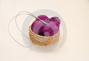 Balls of colored knitting threads and knitting needles on a white background