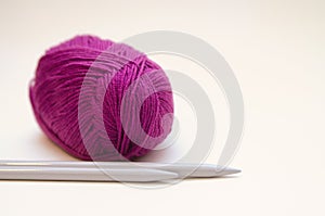 Balls of colored knitting threads and knitting needles on a white background