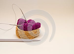 Balls of colored knitting threads and knitting needles on a white background