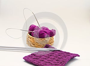 Balls of colored knitting threads and knitting needles on a white background