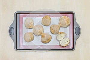 Balls of dough on a silicone baking mat, on an iron tray