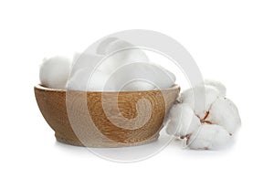 Balls of fluffy cotton in wooden bowl and flower