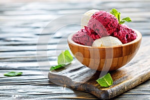 Balls of lemon ice cream and berries in a wooden bowl.
