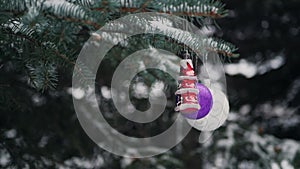 Balls on snow-covered branches of the Christmas tree, slow motion shooting