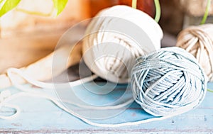 Balls of white and beige yarn on light blue wood table. Threads of high quality wool for macrame and handicrafts