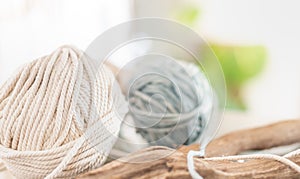 Balls of white and beige yarn on light wood table. Threads of high quality wool for macrame and handicrafts