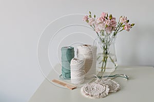 Balls of white and green yarn on white table. Handmade macrame braiding. Female hobby. Selective focus, web banner