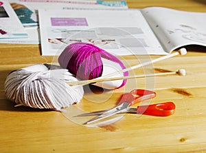 Balls of wool and wooden knitting needles on the table.