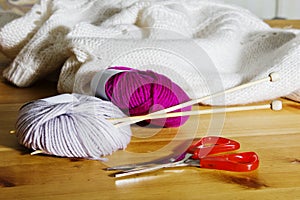 Balls of wool and wooden knitting needles on the table.