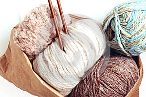 Balls of woolen yarn and knitting needles in a craft eco bag on a white background