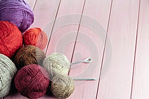 Balls of yarn in different colors with knitting needles on a background of pink