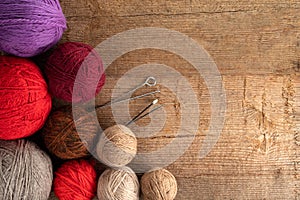 Balls of yarn in different colors with knitting needles on a background of rough wood