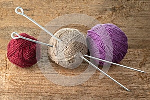 Balls of yarn in different colors with knitting needles on a background of rough wood