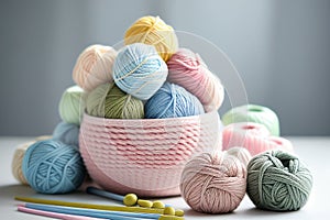 Balls of yarn in light pastel colors in knited backet. Skeins of yarn, needles and tools for needlework