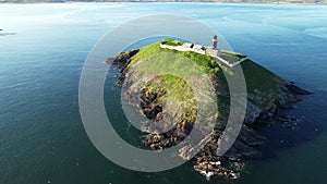 The Ballycotton lighthouse isolated in the middle of the sea on a cloudless calm summer day