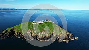 The Ballycotton lighthouse isolated in the middle of the sea on a cloudless calm summer day