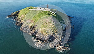 The Ballycotton lighthouse isolated in the middle of the sea on a cloudless calm summer day