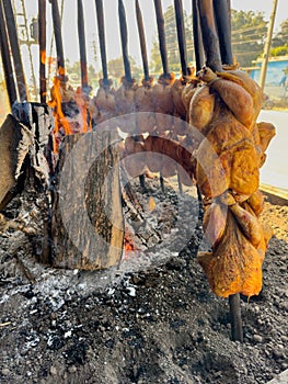 Balochi chicken sajji cooking over open fire in Pakistan