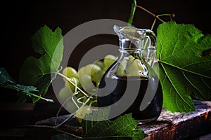 Balsamic vinegar in a glass jug, vintage wooden background, rust