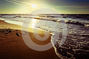 Baltic sea coast with waves breaking on the beach at sunset. Scenic picturesque summer seascape.
