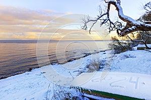 Baltic Sea coast in winter, fishing boat with an inscription on the snow 2024. Happy New Year 2021