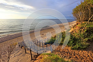 Baltic Sea shore wooded cliff and beach during colorful sunset