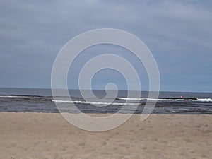 Baltic sea waves on the sand beach. Red safety deep water buoy