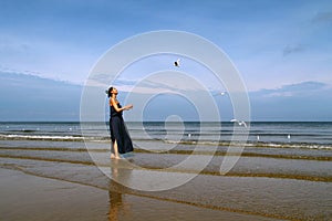 Baltic sea, woman in summer dress feeding white gulls