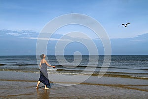 Baltic sea, woman walking along the beach and feeding white gu