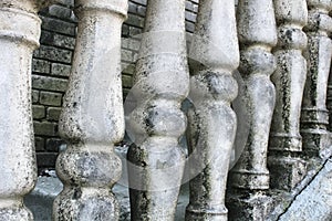Balusters made of stone on the old historic staircase. Ruins of vintage balusters. Gray, weathered stone balusters. The