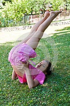 Bambina che fa ginnastica sul prato photo