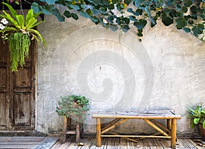 Bamboo bench with decorative plant on concrete wall background