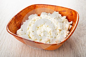 Bamboo bowl with defatted cottage cheese on wooden table